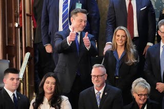 Elon Musk gesticula enquanto se sente para assistir ao discurso